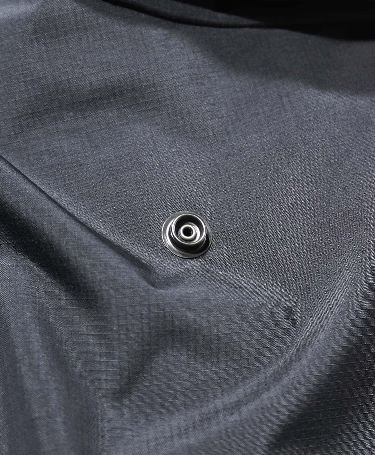 走行時のフードのばたつきを抑えるために背中部分で固定できるドットボタンを配置。